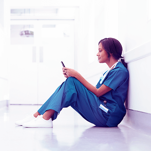 A medical professional sitting in corridor using phone