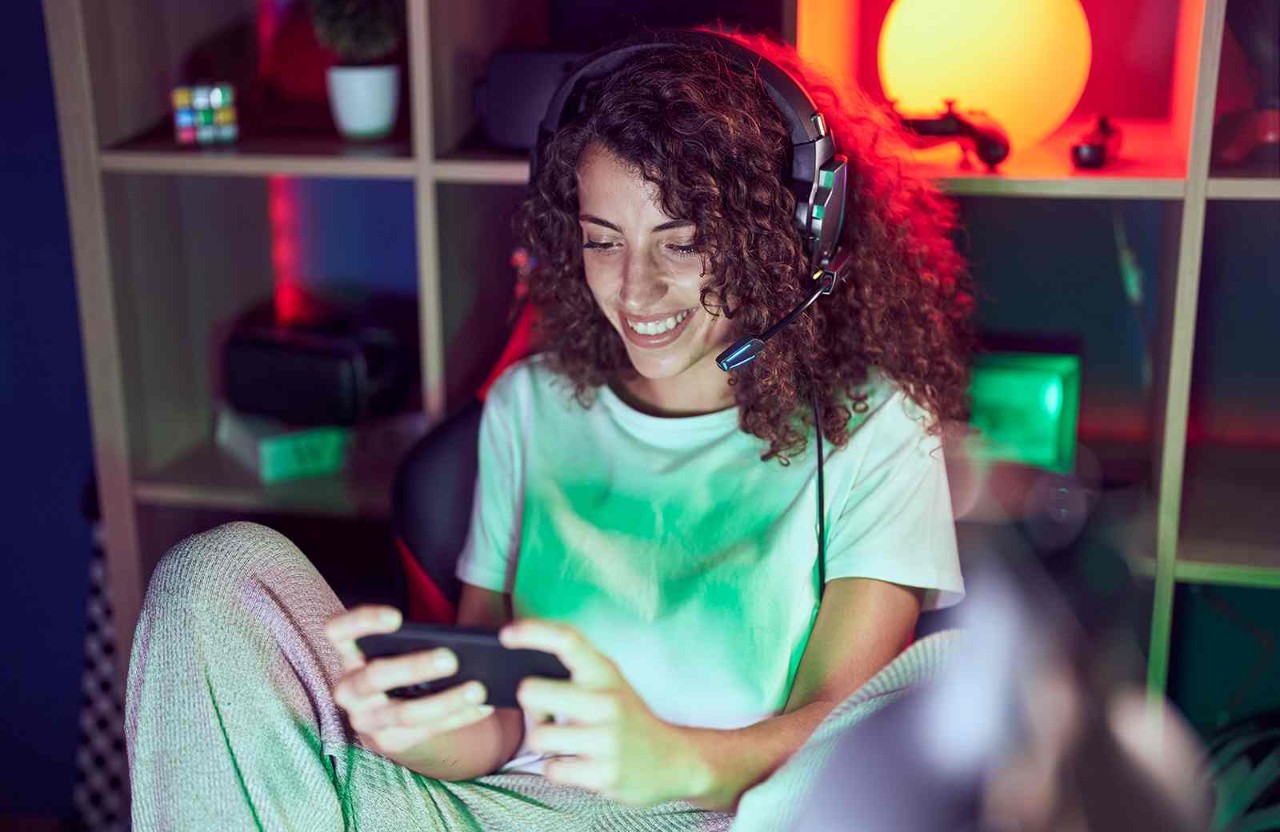 Person gaming wearing headset and holding a phone