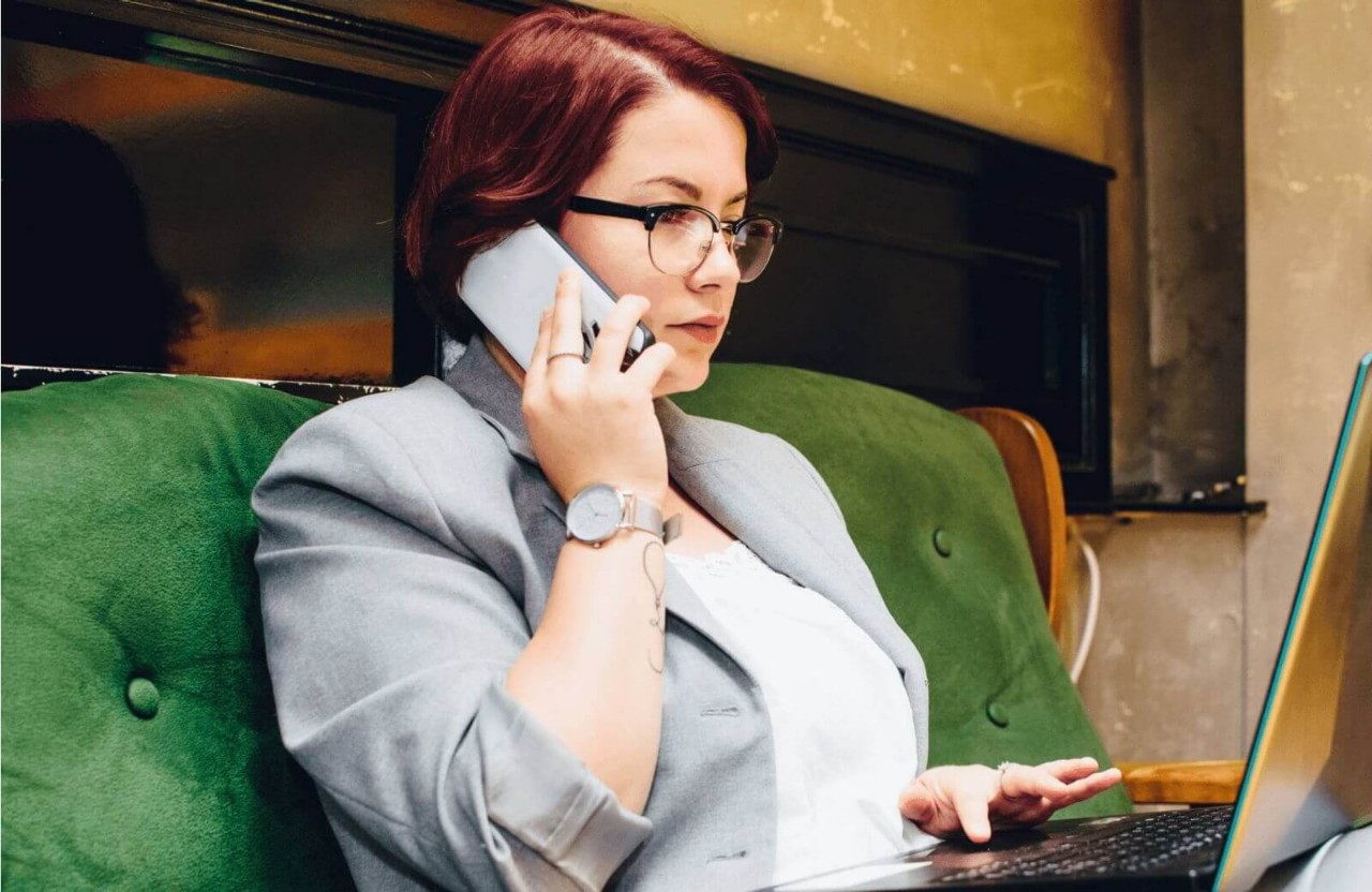 Business woman using her phone while on a laptop