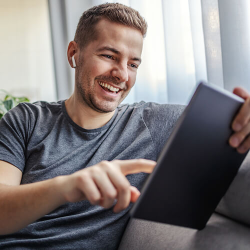 Man sitting on a sofa, holding a tablet.