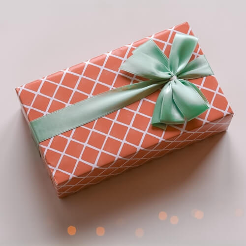 Gift wrapped in red and gold checked paper with a green ribbon tied with a bow