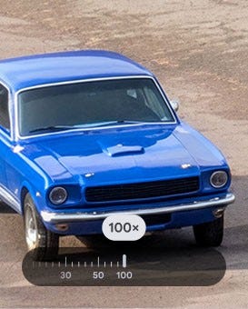 A highly zoomed-in view of a bright blue vintage car, parked on a gravel surface showing the power of Super Res Zoom on Pixel