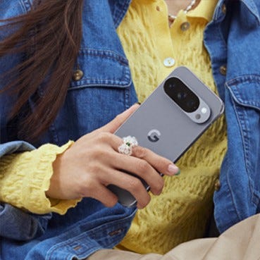 A close-up shot shows a person's hands holding a Pixel 10 Pro. in Moonstone