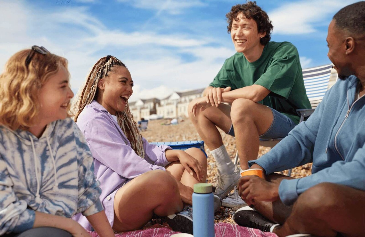 Four friends sitting on a beach laughing